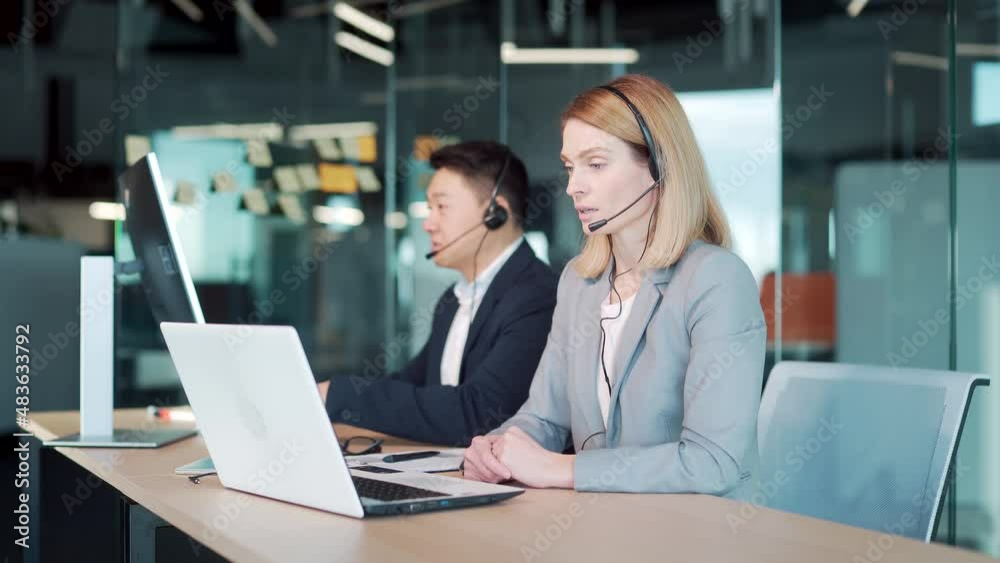 call center employee provide help to client distantly. Asian male customer services agent with headset working in online store helpline, smiling and talking to colleague Business people support remote call center employee provide help to client distantly. Asian male customer services agent with headset working in online store helpline, smiling and talking to colleague Business people support remote