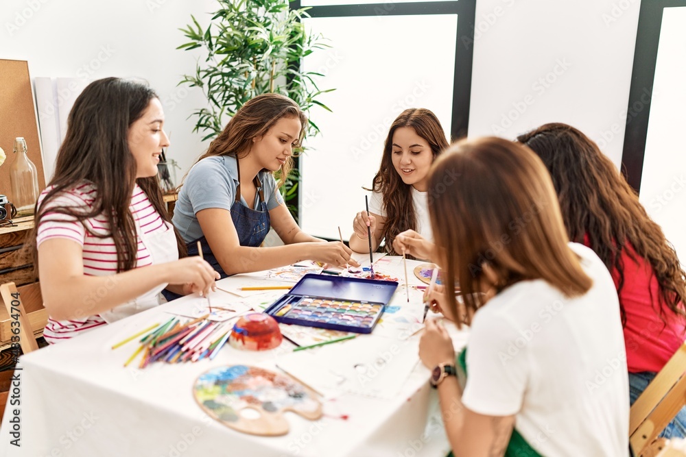 Group of women smiling happy drawing sitting on the table at art studio.