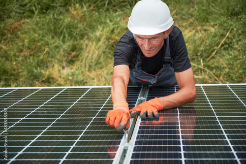 Worker installing solar panel. Renewable and ecological energy. Idea of environment safe. Modern technology and innovation. European man wearing working gloves, workwear and helmet. Top view