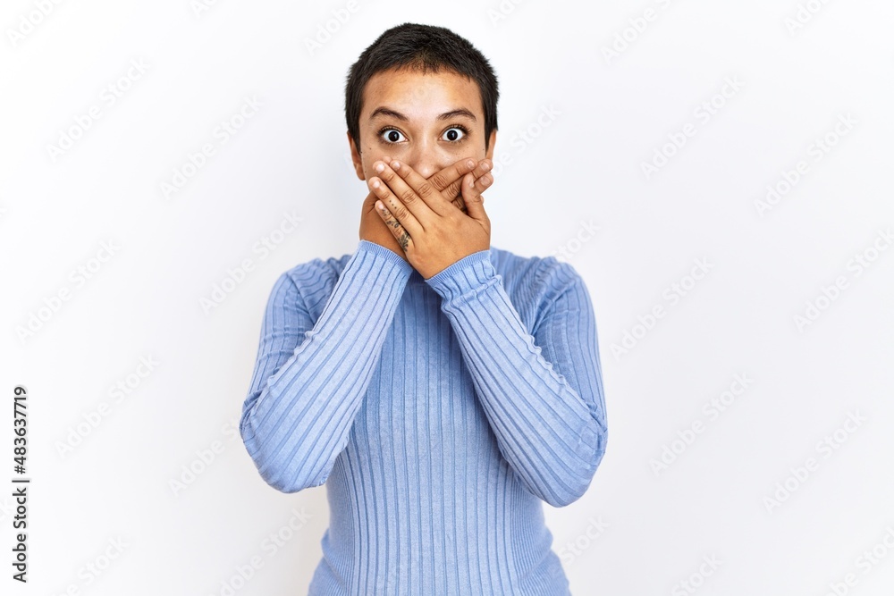 Young hispanic woman with short hair standing over isolated background shocked covering mouth with hands for mistake. secret concept. Young hispanic woman with short hair standing over isolated background shocked covering mouth with hands for mistake. secret concept.