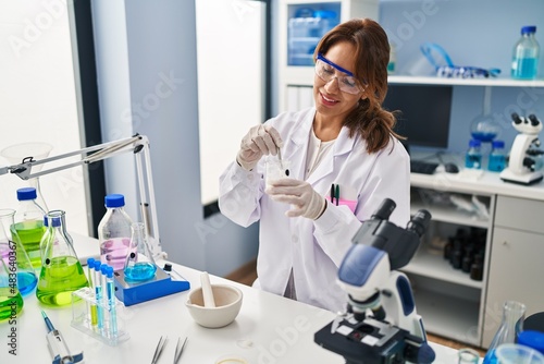 Young latin woman wearing scientist uniform working at laboratory