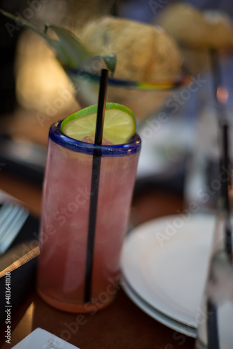 table setting in restaurant, pink cocktail with lime and a straw