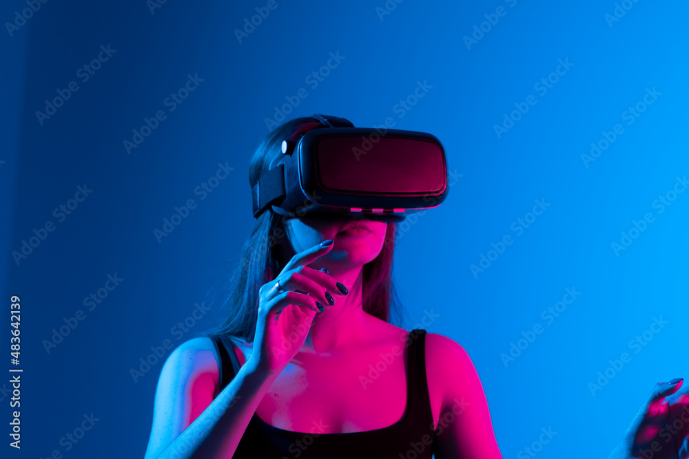 Young attractive brunette woman wearing VR goggles and enjoying amazing experience playing and having fun in virtual reality video game. Young attractive brunette woman wearing VR goggles and enjoying amazing experience playing and having fun in virtual reality video game.