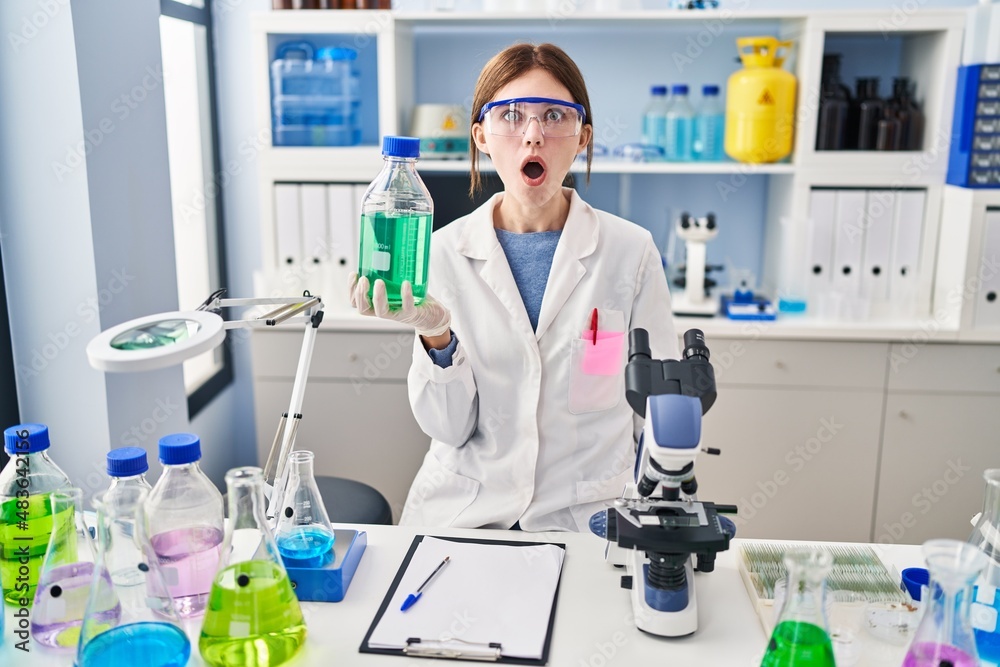 Young brunette woman working at scientist laboratory scared and amazed with open mouth for surprise, disbelief face Young brunette woman working at scientist laboratory scared and amazed with open mouth for surprise, disbelief face