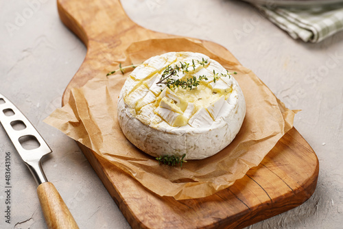 Φωτογραφία Oven baked camembert cheese with lye baguette bread on wooden board, grey concrete surface