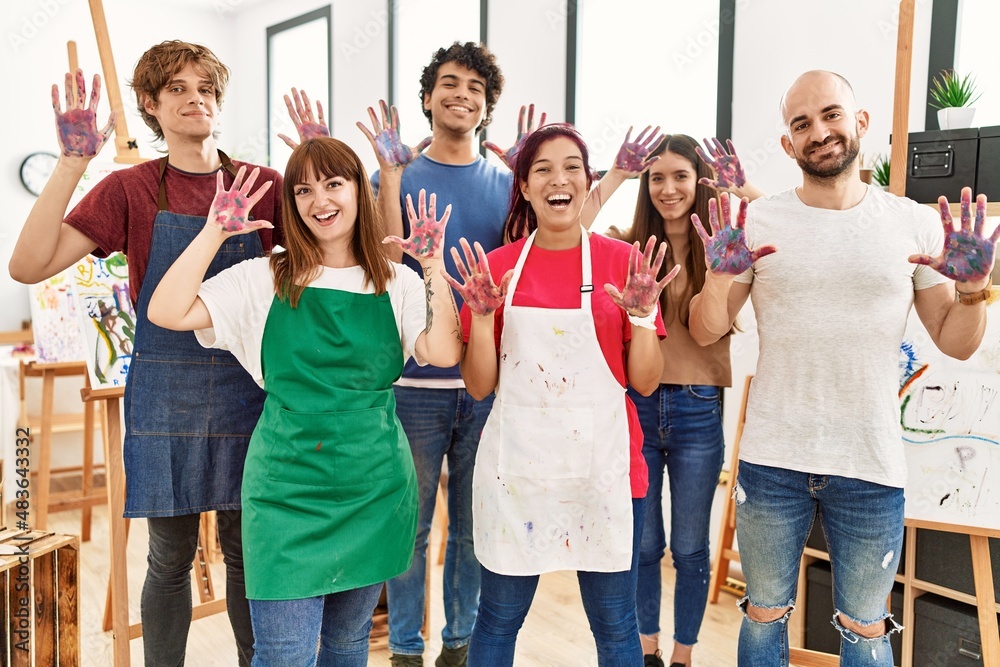 Fototapeta premium Group of people showing painted palm hands looking to the camera standing at art studio.
