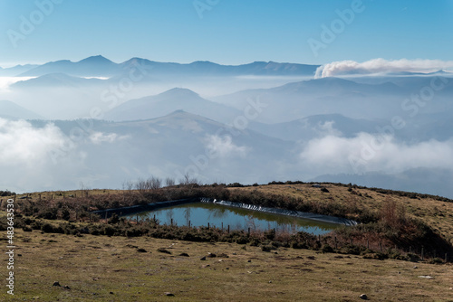 Montanha de La Rhune em Ascain com uma represa de água e com mais montanhas ao fundo com nevoeiro nos altos photo