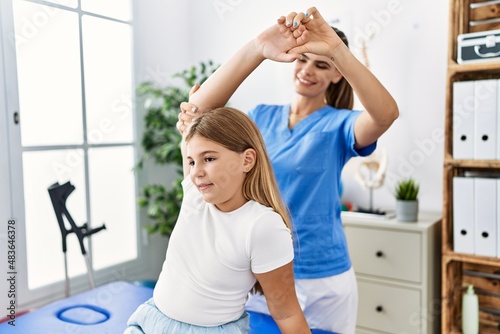 Woman and girl physiotherapist and patient having rehab session stretching arm at physiotherapy clinic