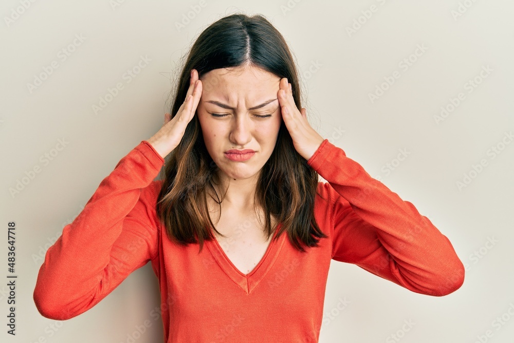 Young brunette woman wearing casual clothes with hand on head for pain in head because stress. suffering migraine. Young brunette woman wearing casual clothes with hand on head for pain in head because stress. suffering migraine.