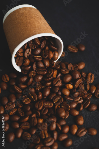 Coffee beans spilling from cup on granite