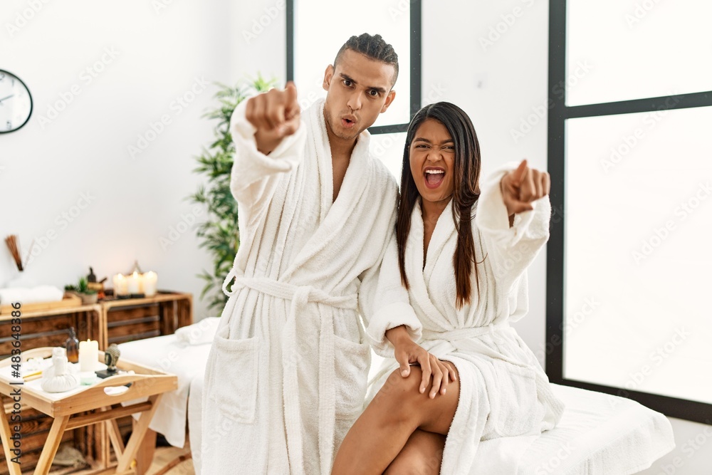 Young latin couple wearing towel standing at beauty center pointing displeased and frustrated to the camera, angry and furious with you Young latin couple wearing towel standing at beauty center pointing displeased and frustrated to the camera, angry and furious with you