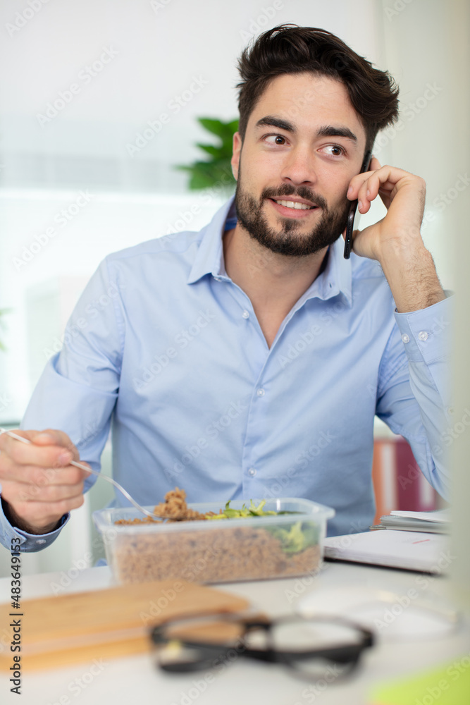 man has business lunch in office talking on mobile