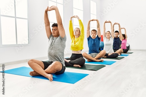 Group of young people concentrated training yoga at sport center.