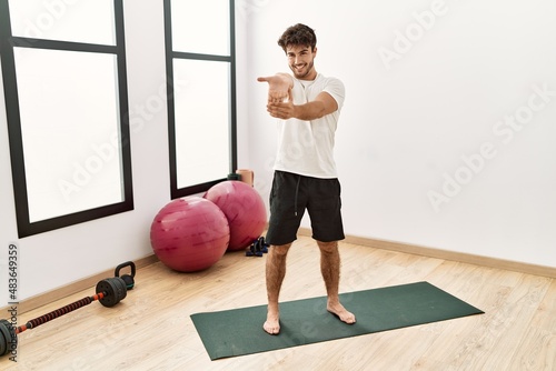 Young hispanic man smiling confident stretching at sport center