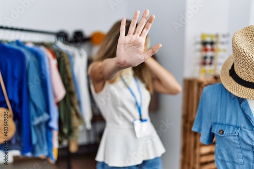 Young blonde woman working as manager at retail boutique covering eyes with hands and doing stop gesture with sad and fear expression. embarrassed and negative concept.