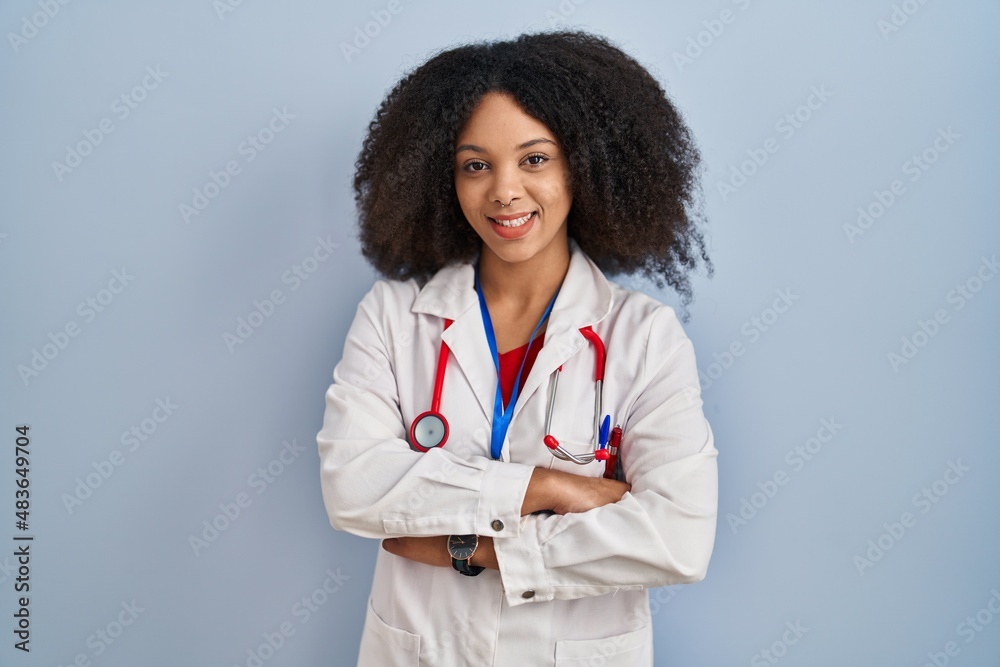 Young african american woman wearing doctor uniform and stethoscope happy face smiling with crossed arms looking at the camera. positive person. Young african american woman wearing doctor uniform and stethoscope happy face smiling with crossed arms looking at the camera. positive person.