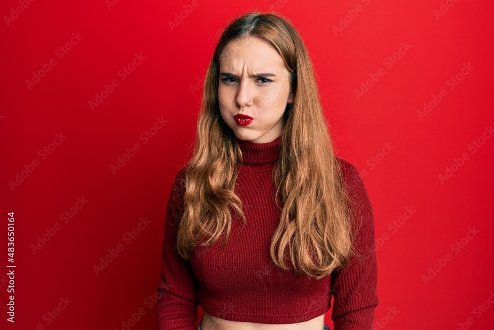 Young blonde woman wearing turtleneck sweater puffing cheeks with funny face. mouth inflated with air, crazy expression. Young blonde woman wearing turtleneck sweater puffing cheeks with funny face. mouth inflated with air, crazy expression.
