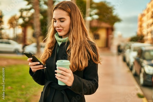 Young blonde girl using smartphone drinking coffee at the city.