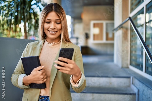 Young latin woman smiling confident using smartphone at street © Krakenimages.com