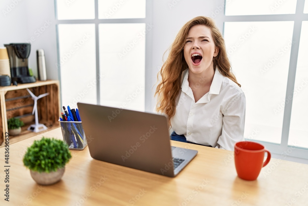Young caucasian woman working at the office using computer laptop angry and mad screaming frustrated and furious, shouting with anger. rage and aggressive concept. Young caucasian woman working at the office using computer laptop angry and mad screaming frustrated and furious, shouting with anger. rage and aggressive concept.