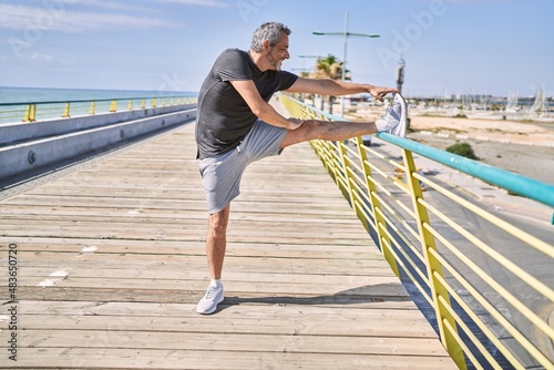 Fototapeta Naklejka Na Ścianę i Meble -  Middle age hispanic man wearing sportswear stretching at street