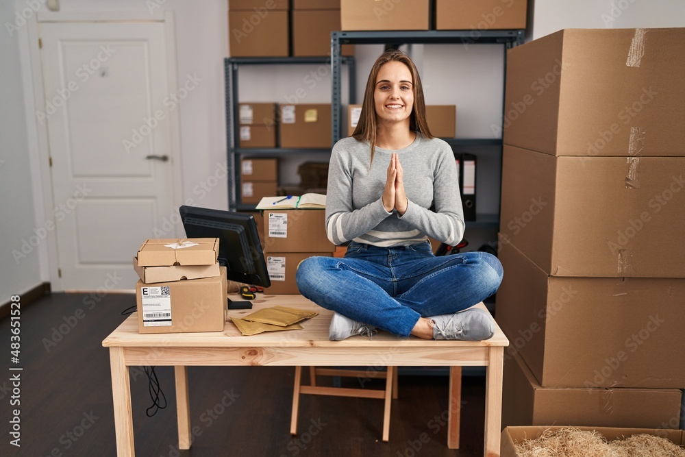 Young blonde woman ecommerce business worker doing yoga sitting on table at office Young blonde woman ecommerce business worker doing yoga sitting on table at office