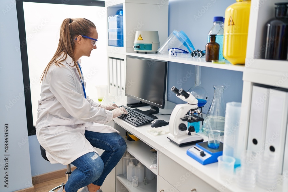 Young blonde woman wearing scientist uniform using computer working at laboratory Young blonde woman wearing scientist uniform using computer working at laboratory