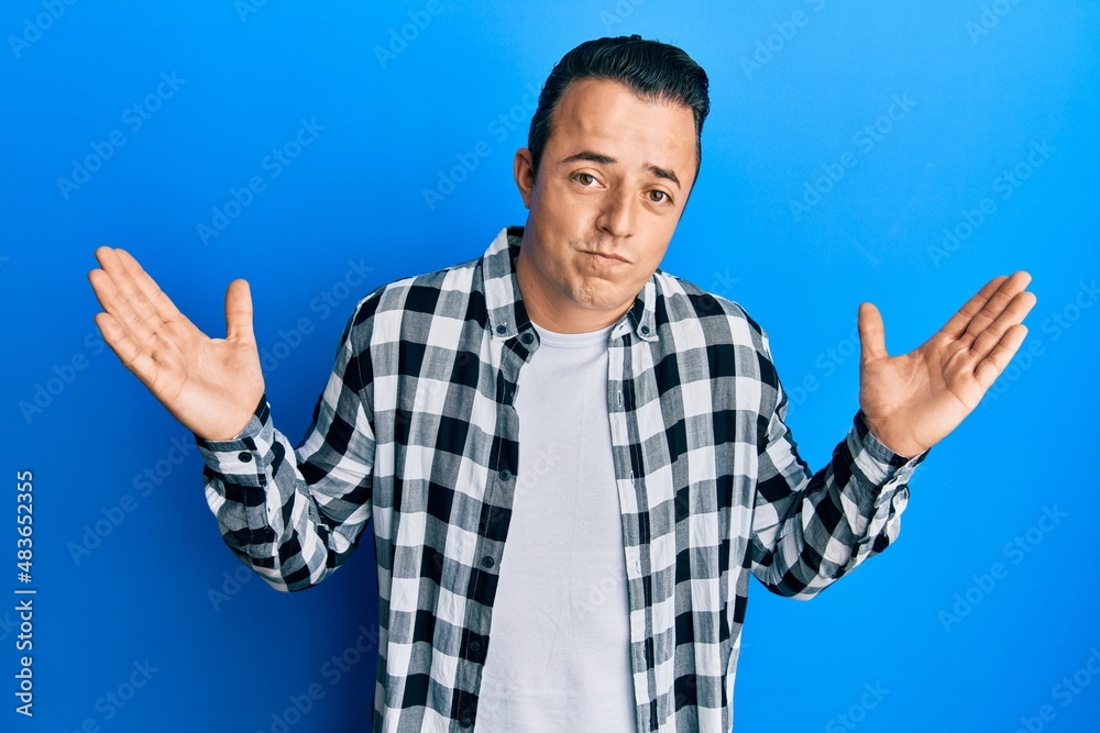 Handsome young man wearing casual shirt clueless and confused with open arms, no idea and doubtful face. Handsome young man wearing casual shirt clueless and confused with open arms, no idea and doubtful face.