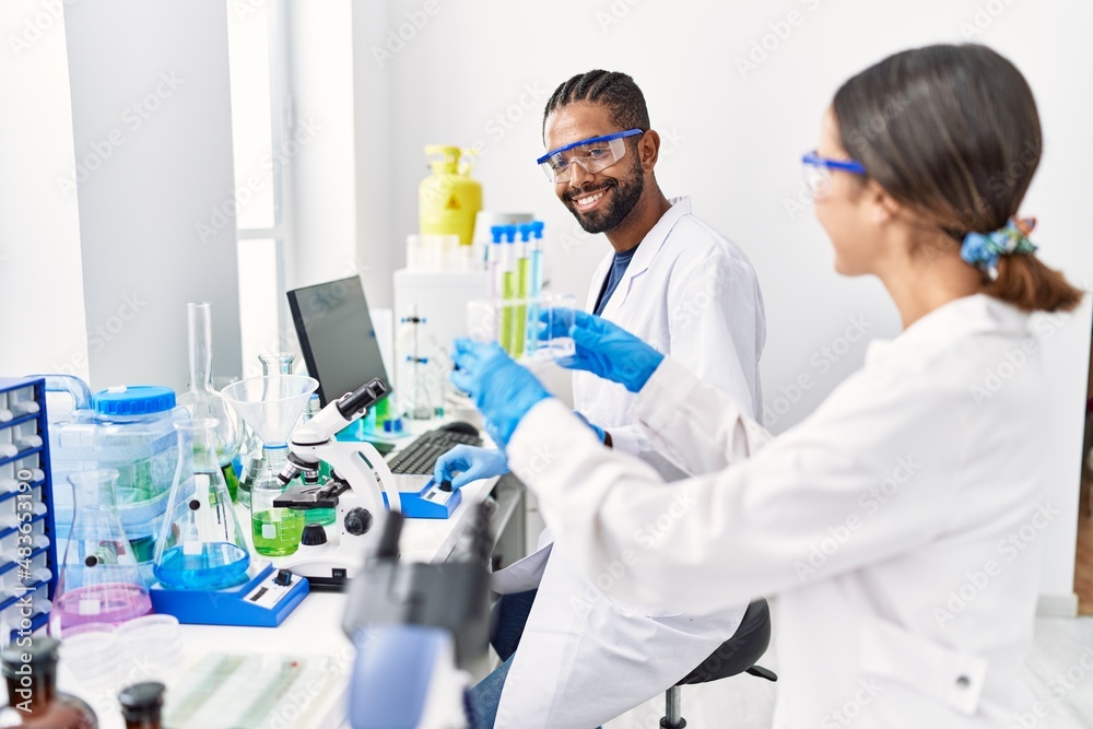 Man and woman scientist partners smiling confident holding test tube at laboratory Man and woman scientist partners smiling confident holding test tube at laboratory