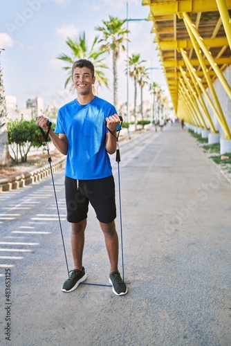 Young hispanic man training with elastic bands outdoors