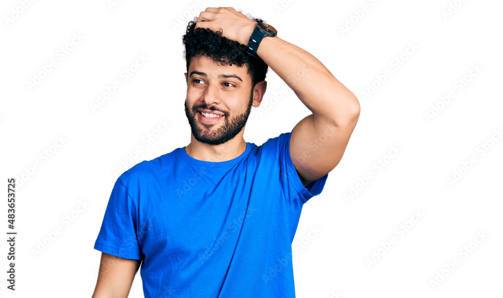 Young arab man with beard wearing casual blue t shirt smiling confident touching hair with hand up gesture, posing attractive and fashionable Young arab man with beard wearing casual blue t shirt smiling confident touching hair with hand up gesture, posing attractive and fashionable