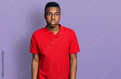 Young african american man wearing casual red t shirt puffing cheeks with funny face. mouth inflated with air, crazy expression.