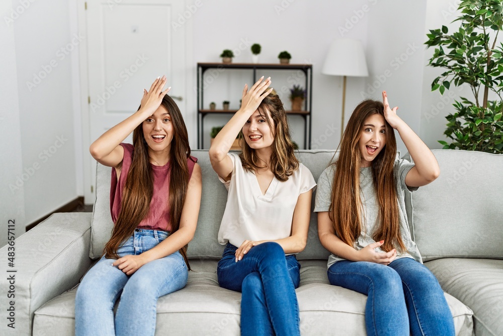 Group of three hispanic girls sitting on the sofa at home surprised with hand on head for mistake, remember error. forgot, bad memory concept. Group of three hispanic girls sitting on the sofa at home surprised with hand on head for mistake, remember error. forgot, bad memory concept.