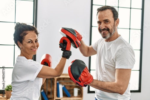 Middle age hispanic couple smiling happy training boxing at home.