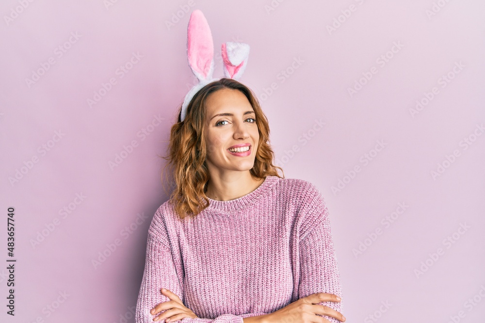 Young caucasian woman wearing cute easter bunny ears happy face smiling with crossed arms looking at the camera. positive person. Young caucasian woman wearing cute easter bunny ears happy face smiling with crossed arms looking at the camera. positive person.