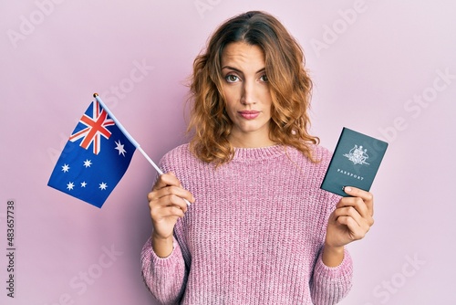 Young caucasian woman holding australian flag and passport skeptic and nervous  frowning upset because of problem. negative person.