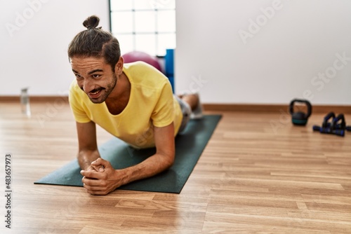 Handsome hispanic man training doing plank at the gym