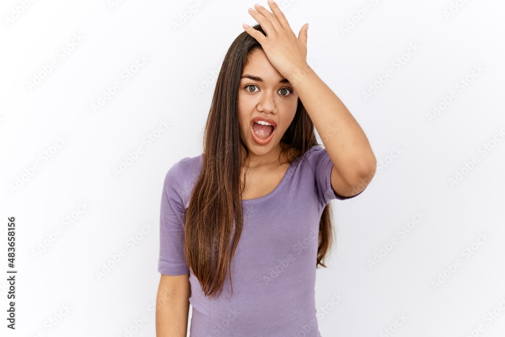 Young brunette woman standing by isolated background surprised with hand on head for mistake, remember error. forgot, bad memory concept. Young brunette woman standing by isolated background surprised with hand on head for mistake, remember error. forgot, bad memory concept.