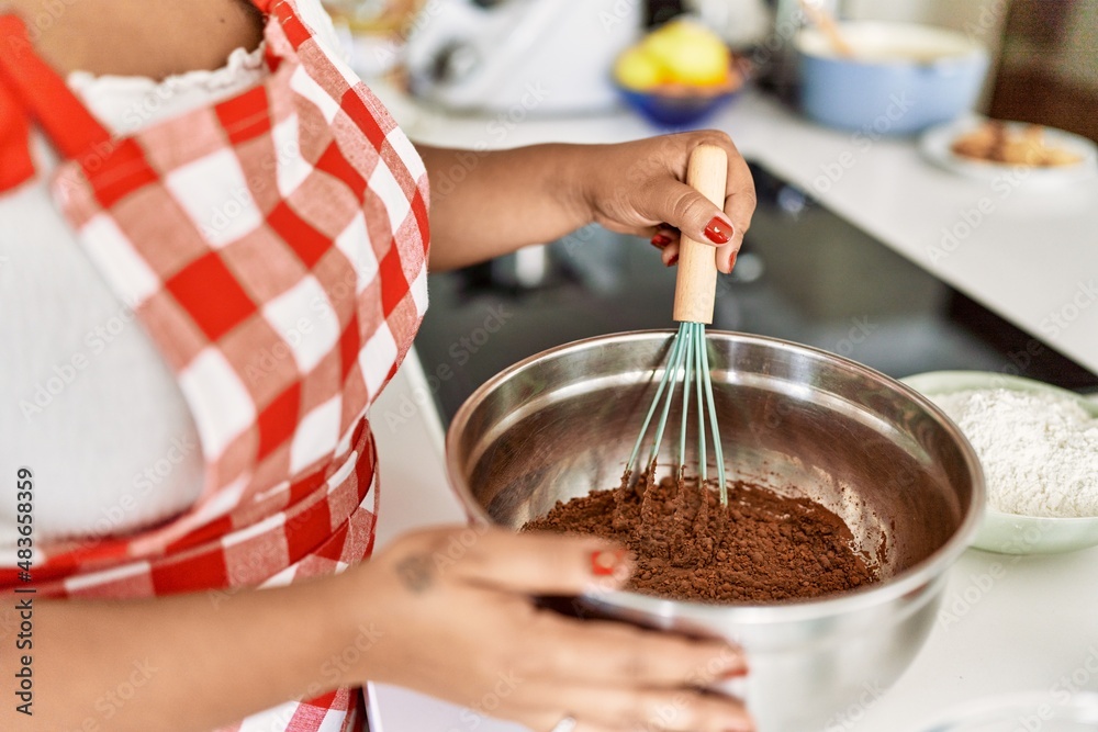 Hispanic brunette woman preparing chocolate cake at the kitchen