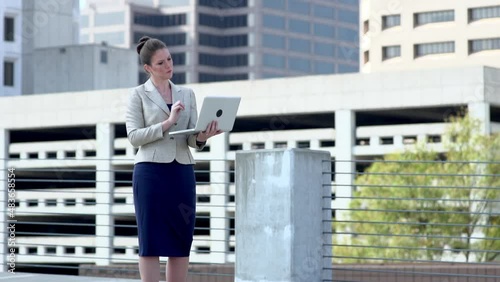 Businesswoman using laptop in modern cityscape