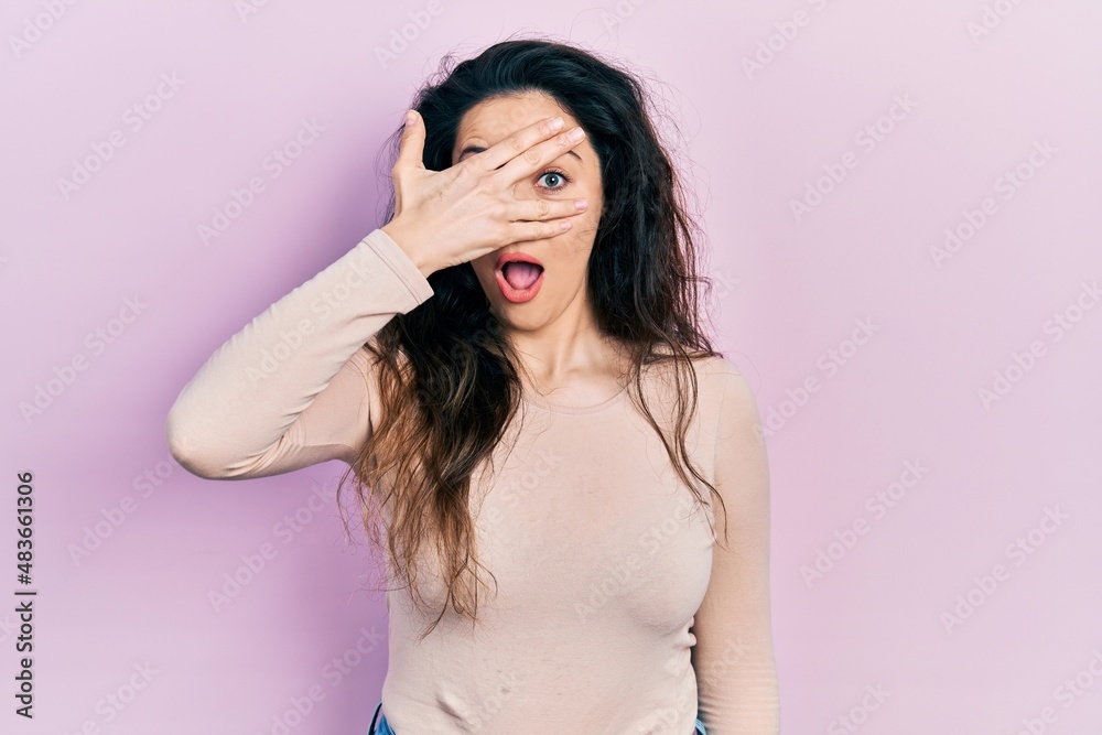 Young hispanic woman wearing casual clothes peeking in shock covering face and eyes with hand, looking through fingers afraid Young hispanic woman wearing casual clothes peeking in shock covering face and eyes with hand, looking through fingers afraid