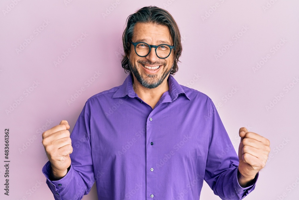 Middle age handsome man wearing casual clothes and glasses celebrating surprised and amazed for success with arms raised and eyes closed