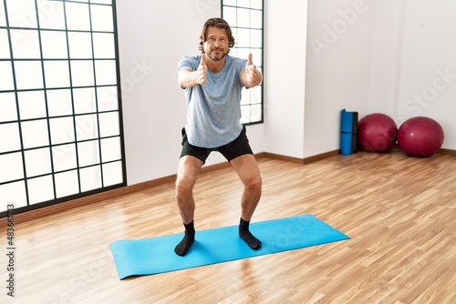 Middle age caucasian man training yoga at sport center