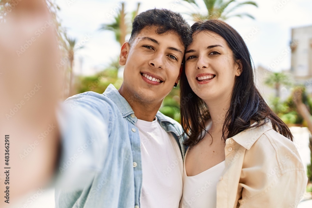 Young hispanic couple of boyfriend and girlfriend together outdoors on a sunny day, smiling in love taking a selfie picture Young hispanic couple of boyfriend and girlfriend together outdoors on a sunny day, smiling in love taking a selfie picture