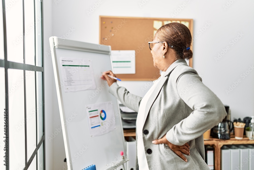 Senior african american woman business worker writing on whiteboard at office