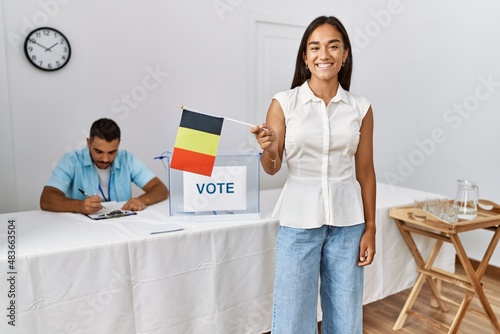 Young belgian voter woman smiling happy holding belgium flag at electoral college.