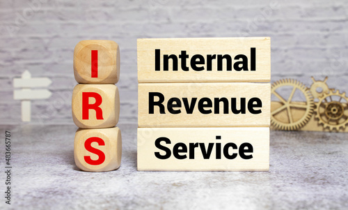 IRS- abbreviation Internal Revenue Service. Written on wooden blocks on a wooden table.