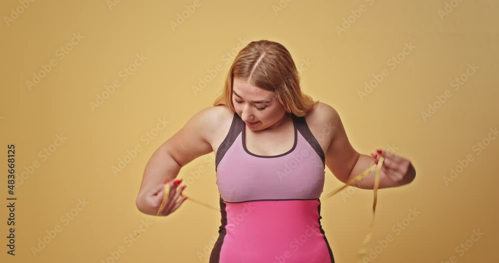 Sad plump sportswoman measuring body with tape Sad plump sportswoman measuring body with tape