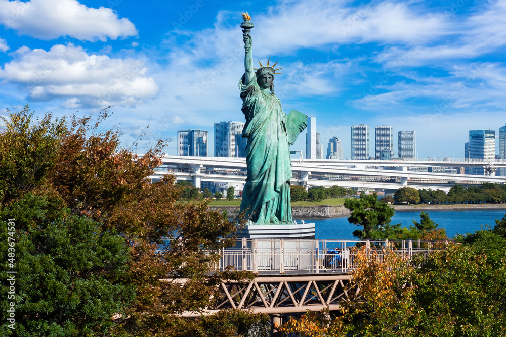 Fototapeta premium Tokyo Odaibo. Japan cityscape. Statue of Liberty on island of Odaiba. City in Tokyo Bay. Odaiba in sunny weather. Statue of Liberty on blue sky backgraund. Tokyo tourism. Vacation in Japan.