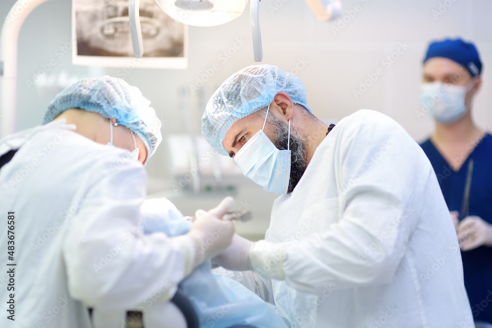 Surgeon and nurse during a dental operation. Anesthetized patient in the operating room. Installation of dental implants in the clinic. Surgeon and nurse during a dental operation. Anesthetized patient in the operating room. Installation of dental implants in the clinic.